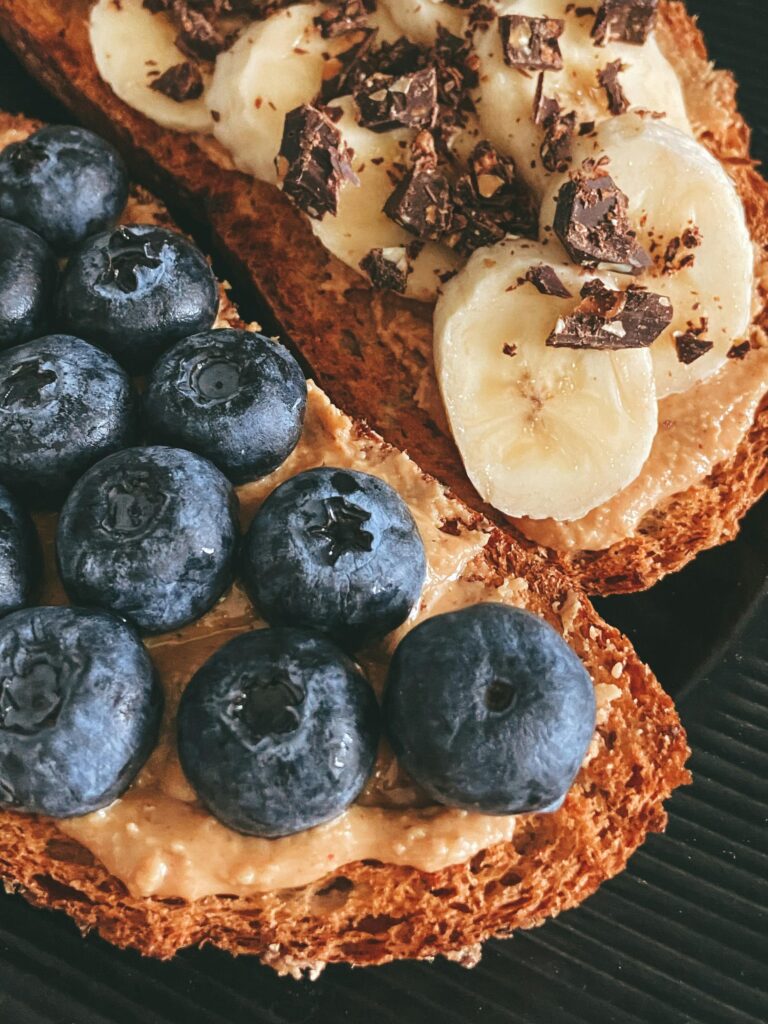 Close-up of toast topped with fresh blueberries, bananas, and peanut butter for a healthy breakfast.