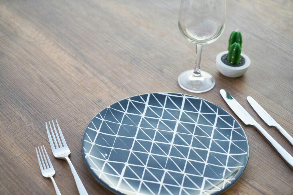 Stylish table setup with a geometric plate, silverware, and potted cactus.